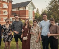 A group of students pose outside the College buildings